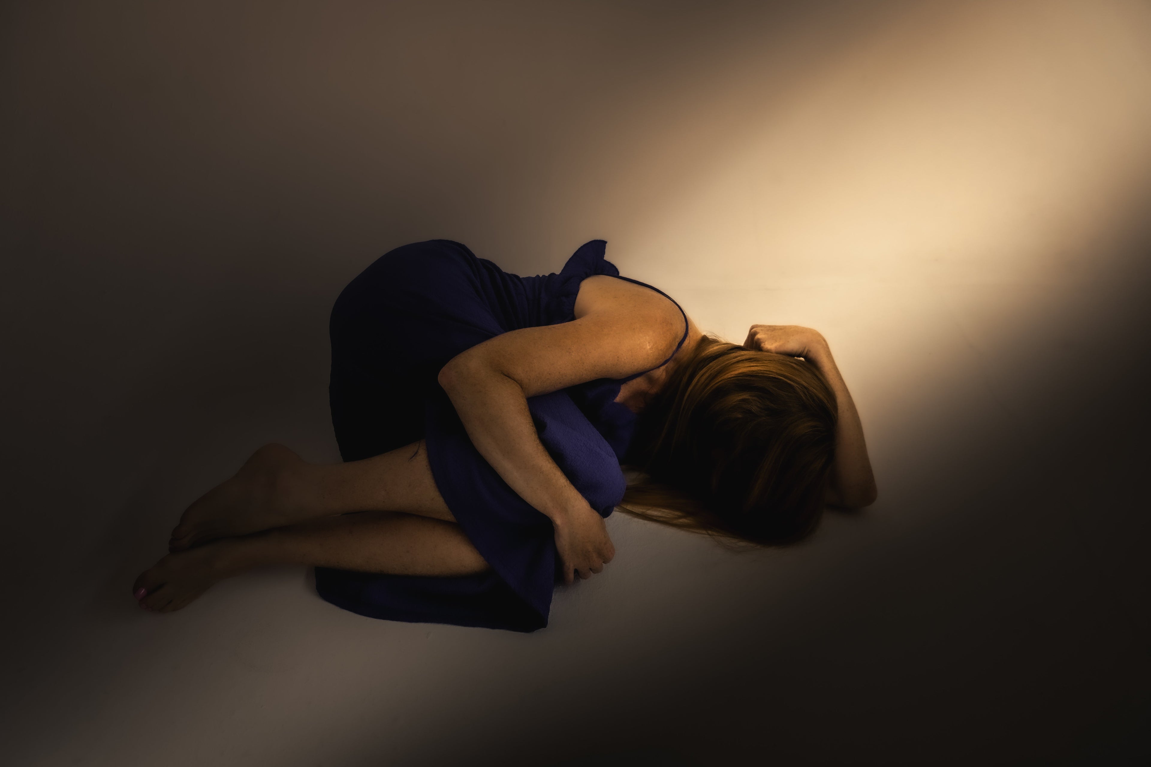 8 signs you are burning out by Amanda Perry. Woman lying on floor in the dark.