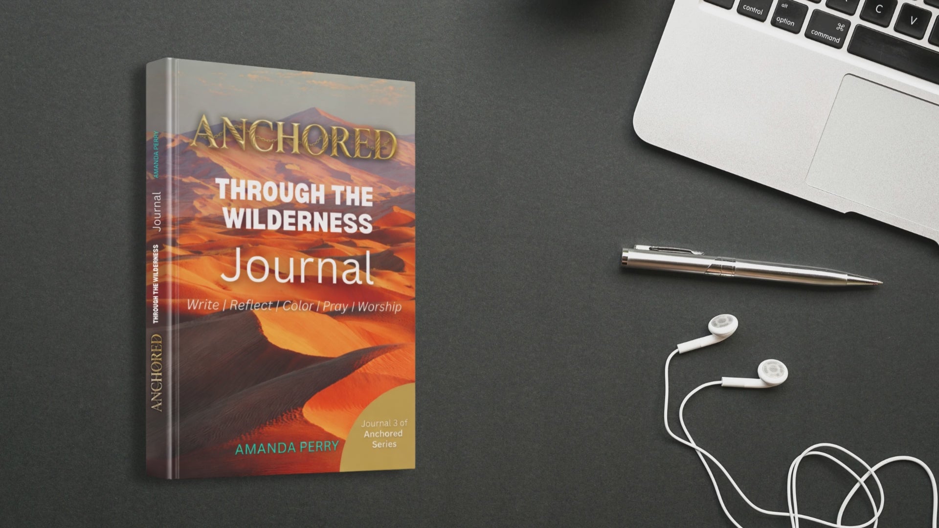 Anchored In the Wilderness Video of the book on a desk next to a laptop and headphones and a pen on a dark background