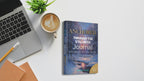 Anchored Through the Stillness book on a desk with laptop. cappucino and pen with desk plant and light background
